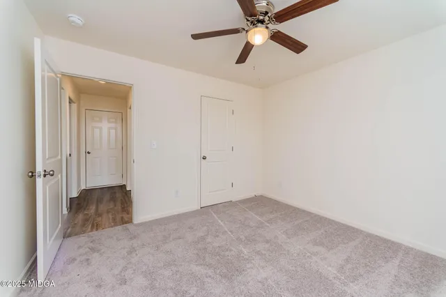 an empty room with closet and a chandelier fan