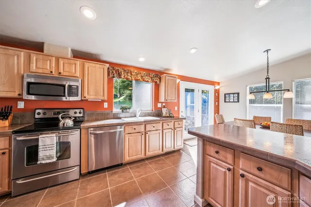a kitchen with stainless steel appliances granite countertop a stove a sink and a microwave