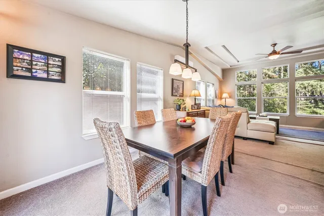 a view of a dining room with furniture a chandelier and large windows