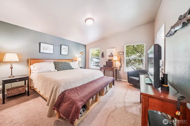 a spacious bedroom with a bed and a flat tv screen next to a window