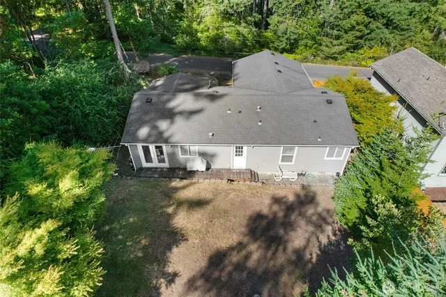 an aerial view of a house with yard and trees all around