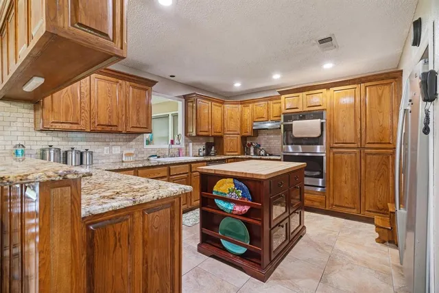 a kitchen with stainless steel appliances granite countertop a stove a sink dishwasher a refrigerator and cabinets with wooden floor