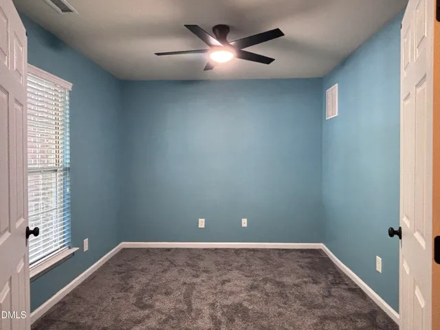 an empty room with closet and a chandelier fan