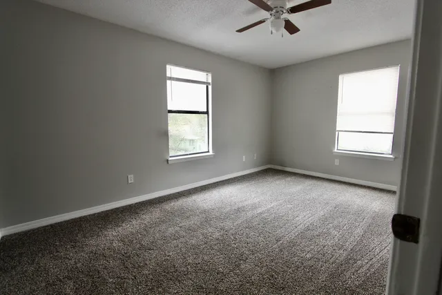 an empty room with windows and fan