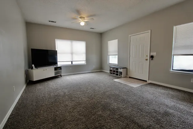 an empty room with windows and ceiling fan