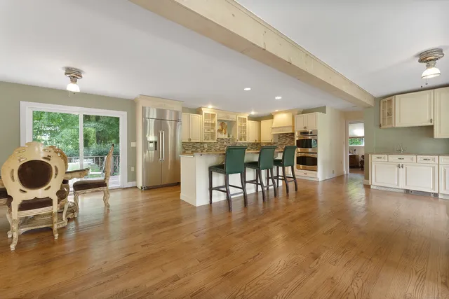 a dining room with furniture and wooden floor kitchen view