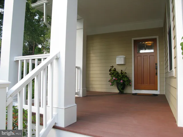 a view of a hallway with wooden floor and a bathroom