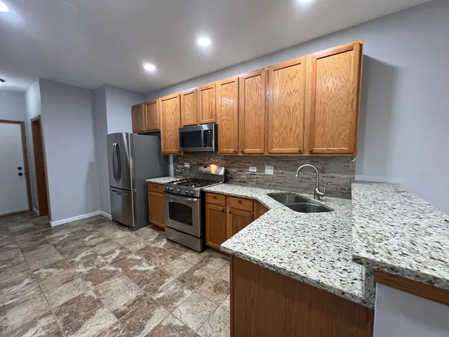 a kitchen with stainless steel appliances granite countertop a stove a sink a refrigerator a counter space and cabinets