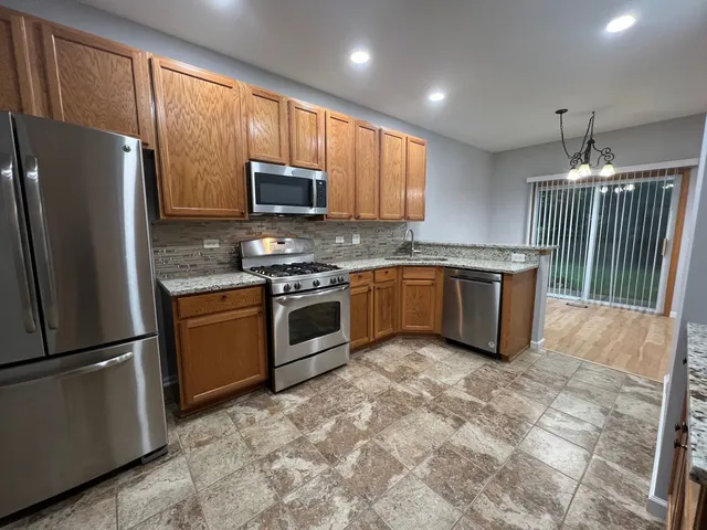 a kitchen with stainless steel appliances granite countertop a stove top oven a sink and a refrigerator