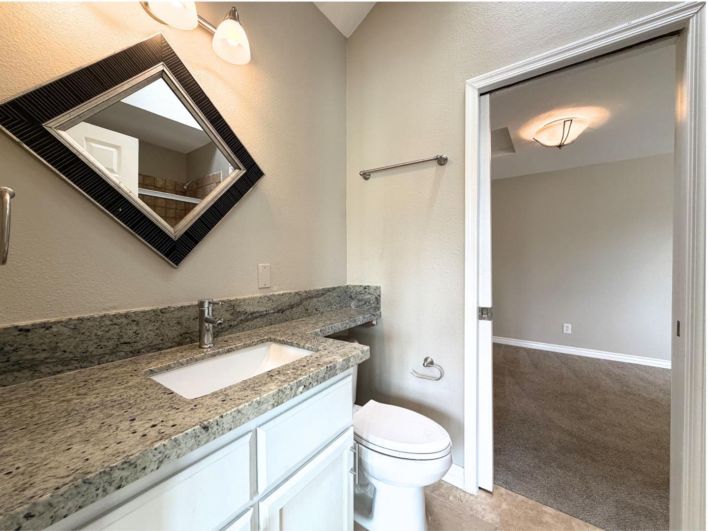 7272 East Gainey Ranch Road, Unit 19 Scottsdale, AZ 85258 - Photo 11 of 13 a bathroom with a granite countertop sink mirror vanity and toilet