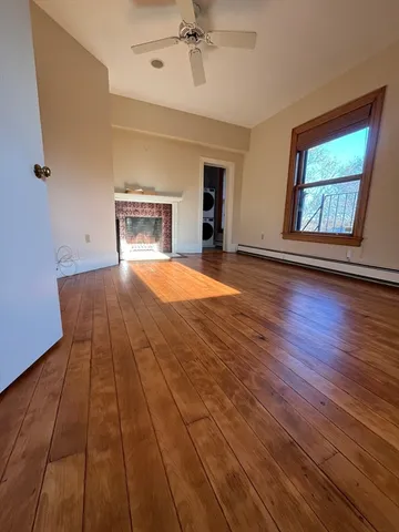 a view of an empty room with a window and wooden floor