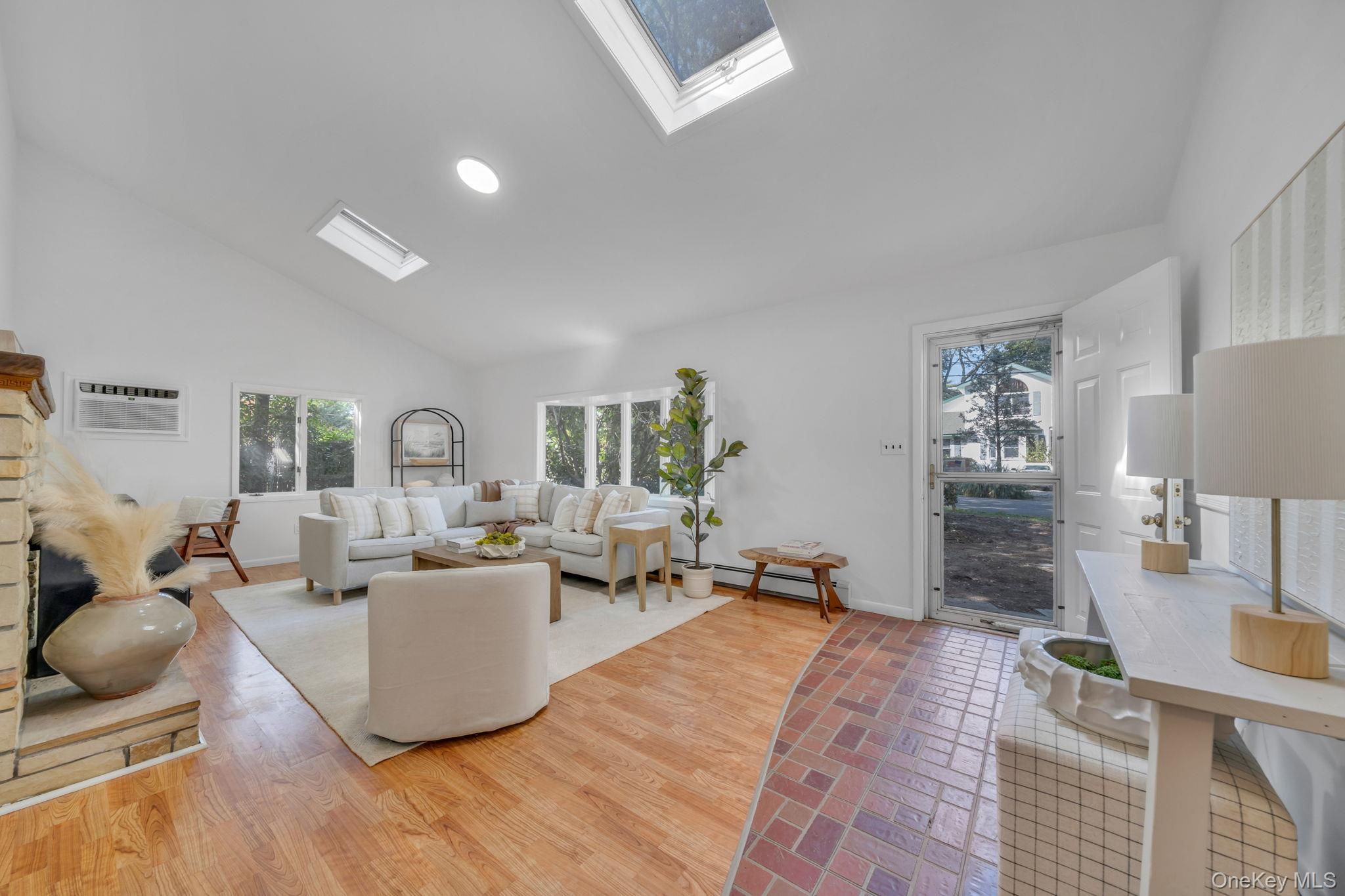 Living room with a skylight, high vaulted ceiling, plenty of natural light, light wood-style floors, and recessed lighting