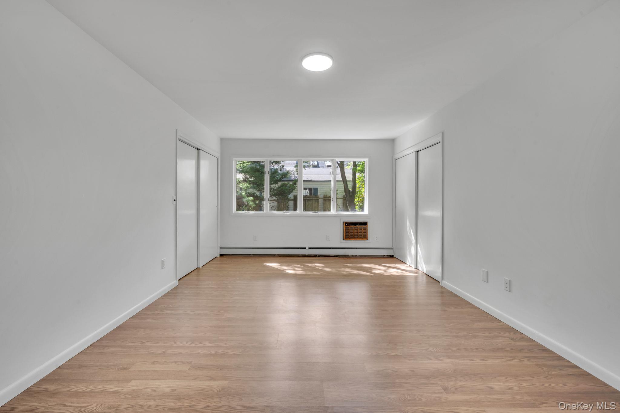 60 Hawthorne Road Rocky Point, NY 11778 - Photo 13 of 23 Unfurnished bedroom with multiple closets, light wood finished floors, and a wall unit AC