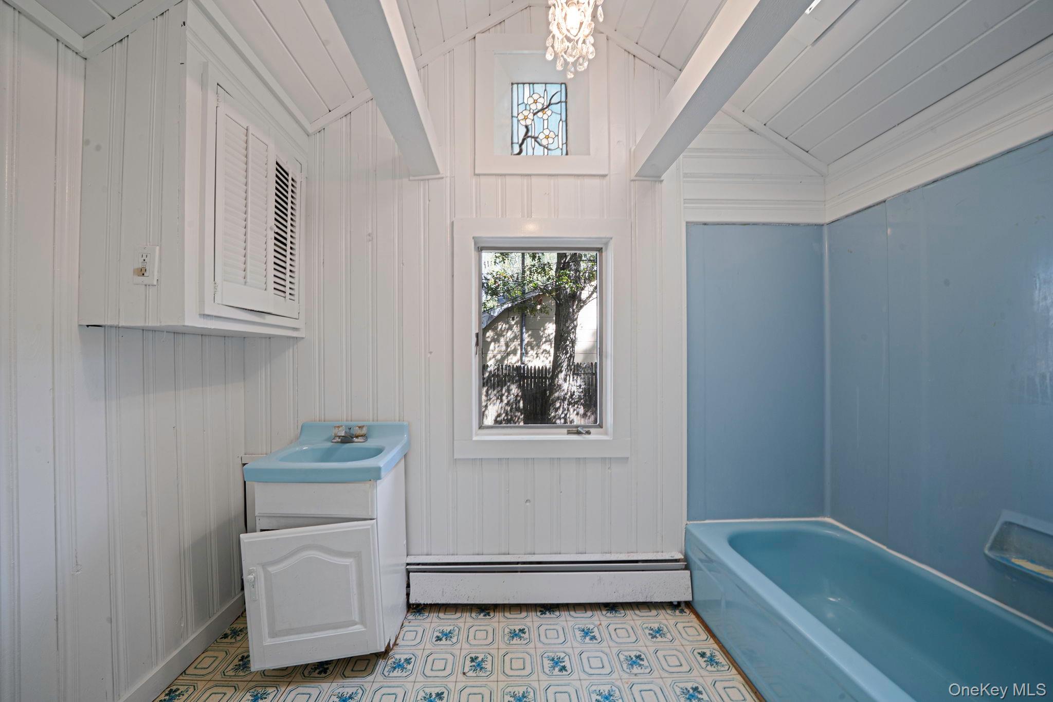60 Hawthorne Road Rocky Point, NY 11778 - Photo 14 of 23 Bathroom with vanity, a baseboard heating unit, a chandelier, wooden walls, and vaulted ceiling