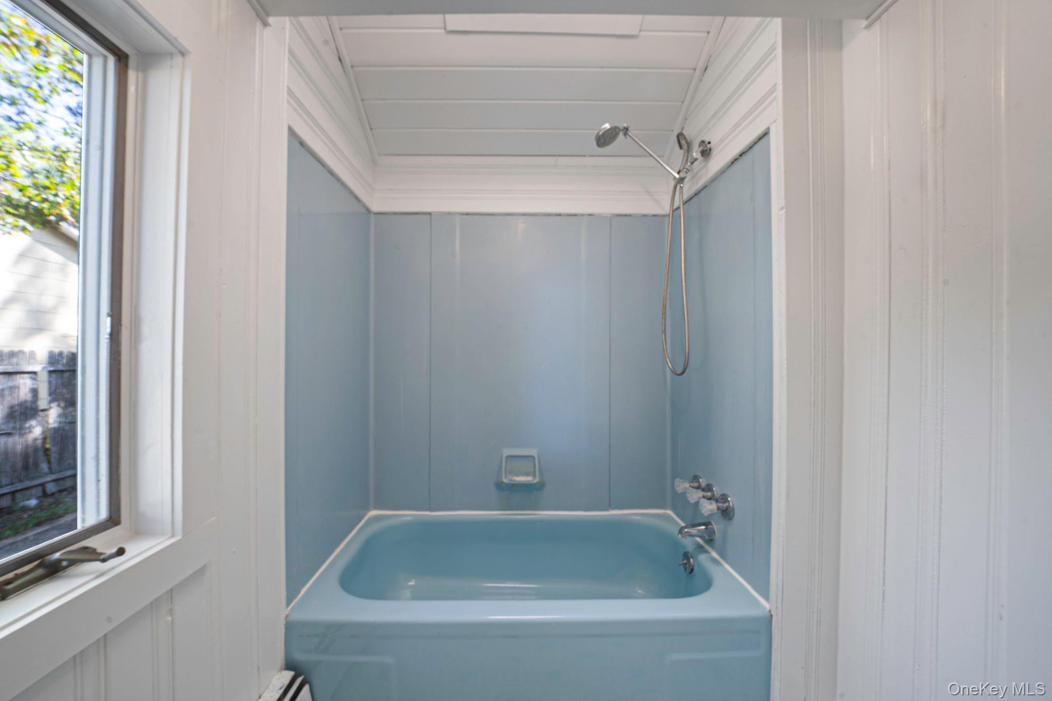 60 Hawthorne Road Rocky Point, NY 11778 - Photo 15 of 23 Bathroom featuring bathing tub / shower combination, wooden walls, and lofted ceiling