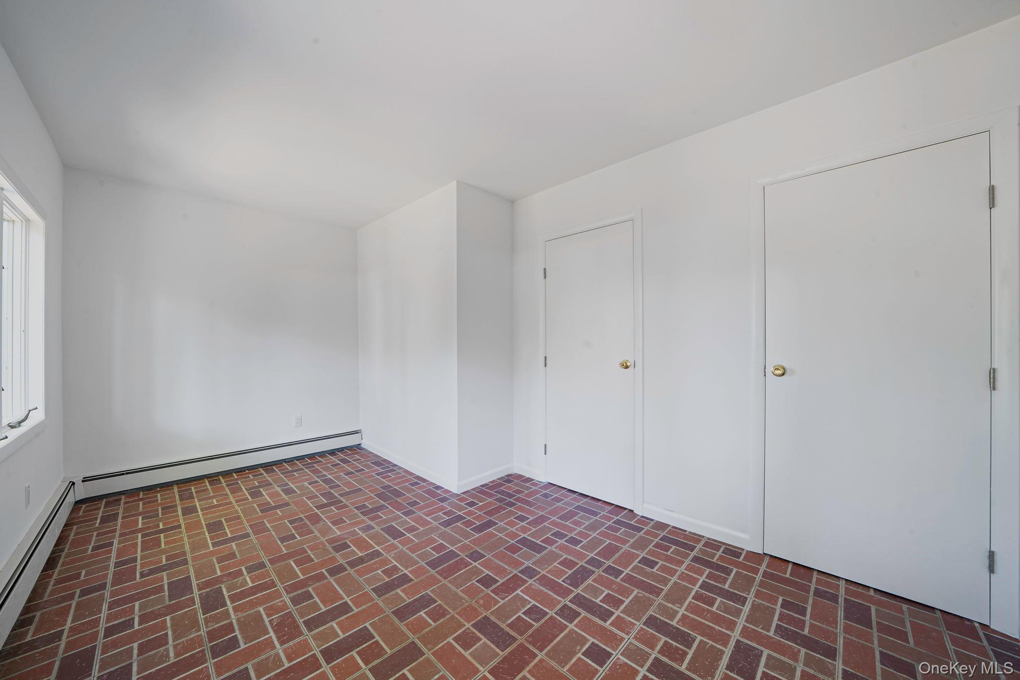 60 Hawthorne Road Rocky Point, NY 11778 - Photo 17 of 23 Unfurnished bedroom with baseboard heating and brick patterned flooring