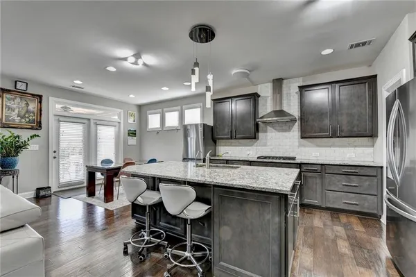 a kitchen with stainless steel appliances granite countertop a sink a stove a refrigerator and chairs