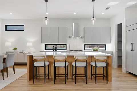 a kitchen with stainless steel appliances granite countertop a dining table chairs stove and refrigerator