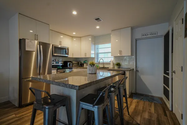 a kitchen with stainless steel appliances granite countertop a refrigerator a sink a stove a dining table and chairs