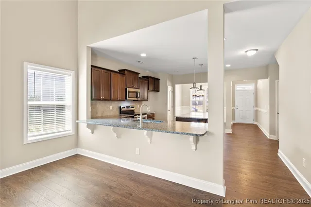 a view of a kitchen with kitchen island a sink wooden floor and a large window