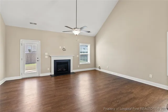 a view of an empty room with wooden floor fireplace and a window