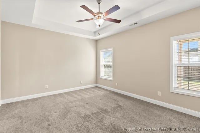 an empty room with windows and fan