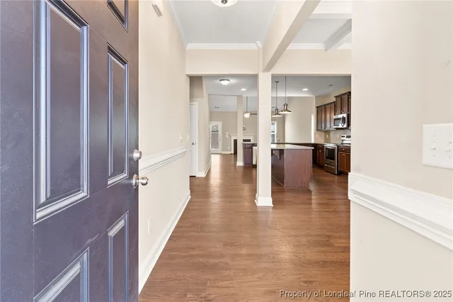 a hallway with wooden floor table and chairs