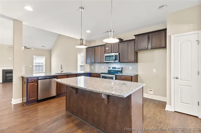 a large kitchen with stainless steel appliances granite countertop a refrigerator a sink dishwasher a oven and a wooden cabinets