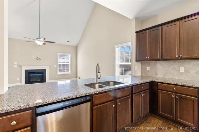 a kitchen with granite countertop a sink dishwasher stove and cabinets