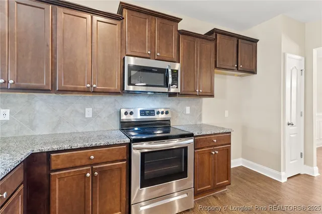 a kitchen with granite countertop wooden cabinets and stainless steel appliances