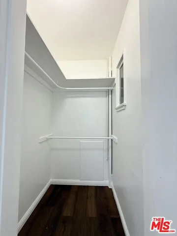a walk in closet with wooden floor