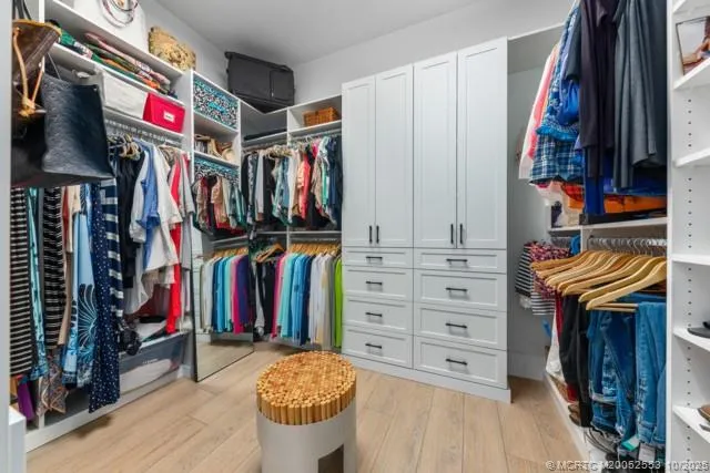 a view of walk in closet with clothes and shoes