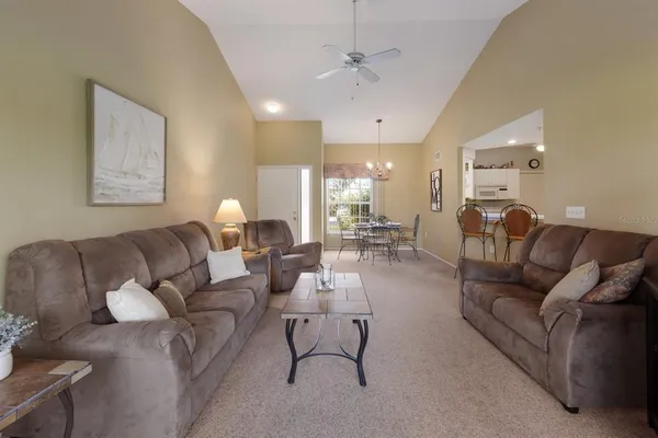 a living room with furniture kitchen view and a chandelier