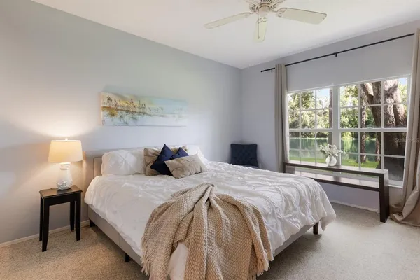 a bedroom with a large bed and a chandelier fan