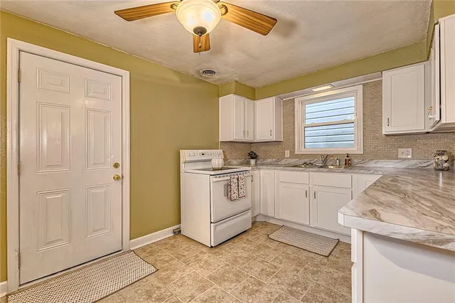 a kitchen with granite countertop white cabinets sink and white appliances