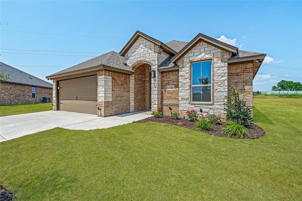 1342 Oleander Drive Tolar, TX 76476 - Photo 1 of 1 French country home with stone siding, concrete driveway, a garage, a front yard, and roof with shingles