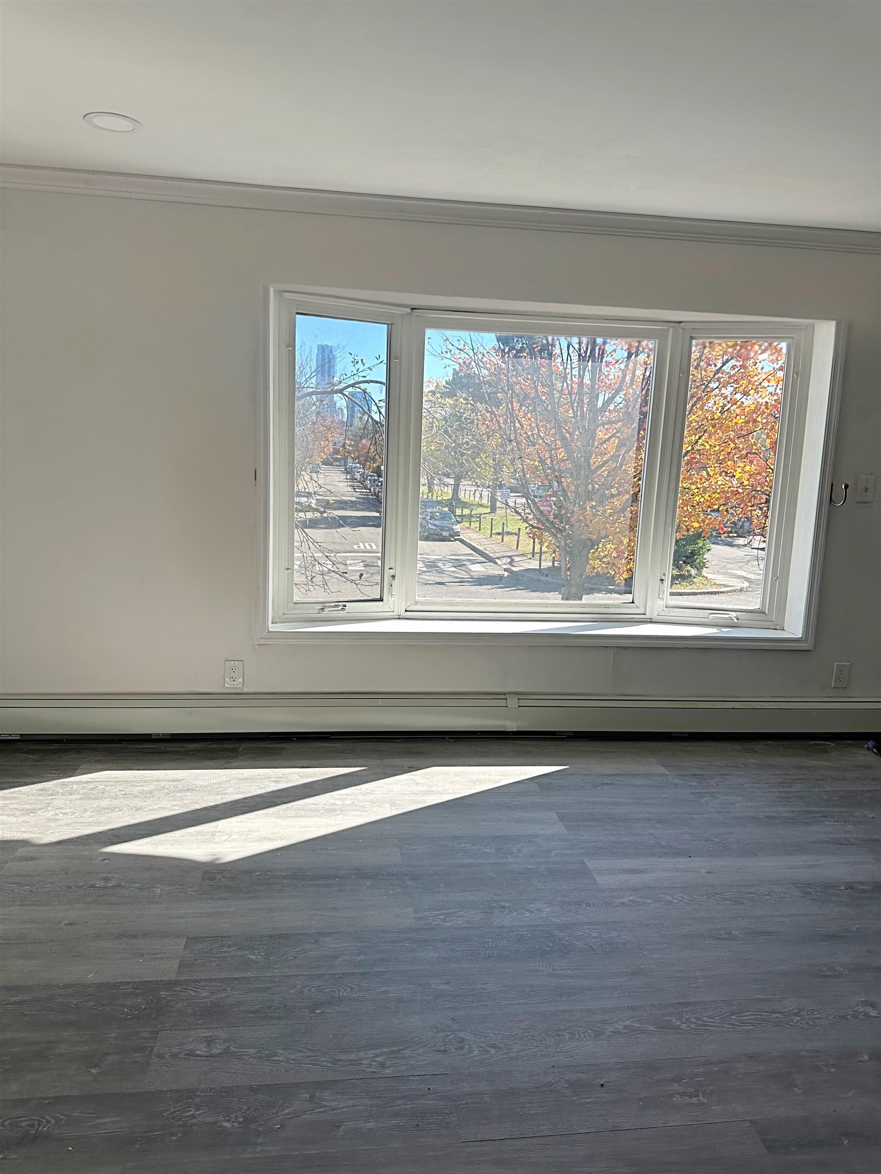 367 Mercer Loop, Unit 2 Jersey City, NJ 07302 - Photo 4 of 8 a view of an empty room with wooden floor and a window