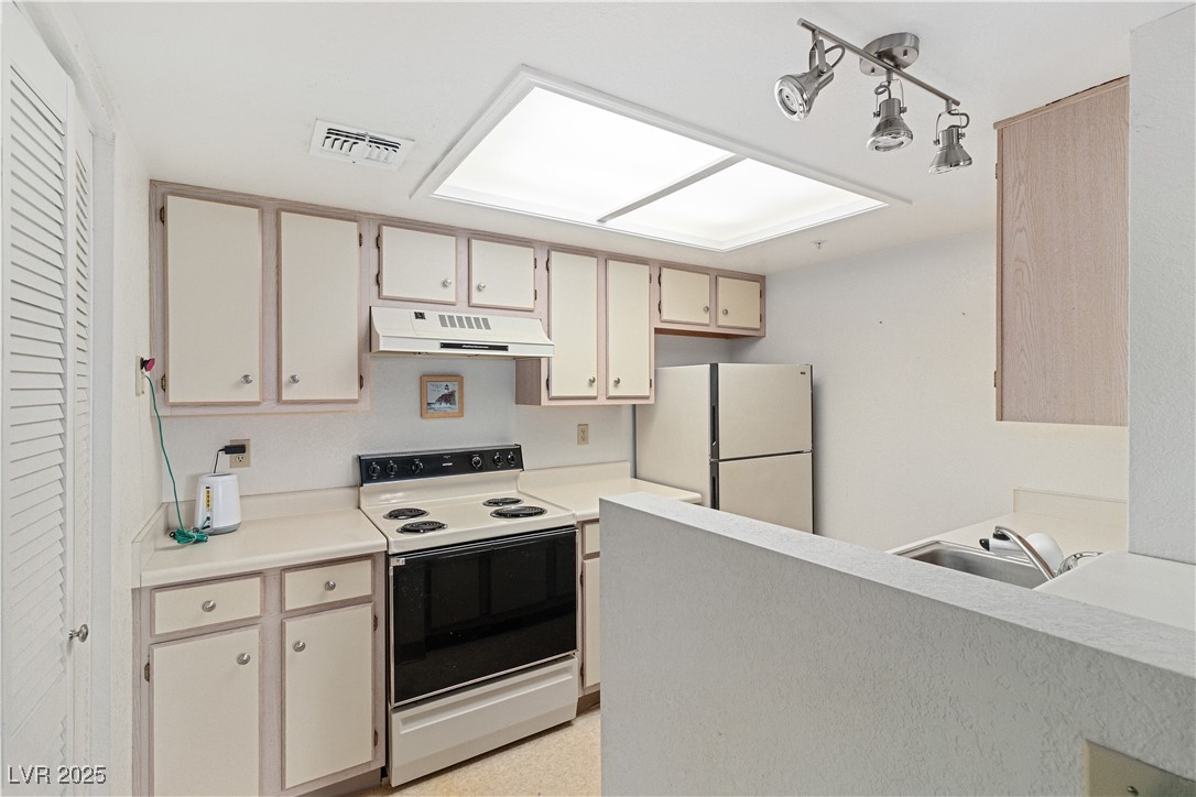 3550 Bay Sands Drive, Unit 1050 Laughlin, NV 89029 - Photo 9 of 71 Kitchen with range with electric stovetop, freestanding refrigerator, light countertops, under cabinet range hood, and cream cabinets