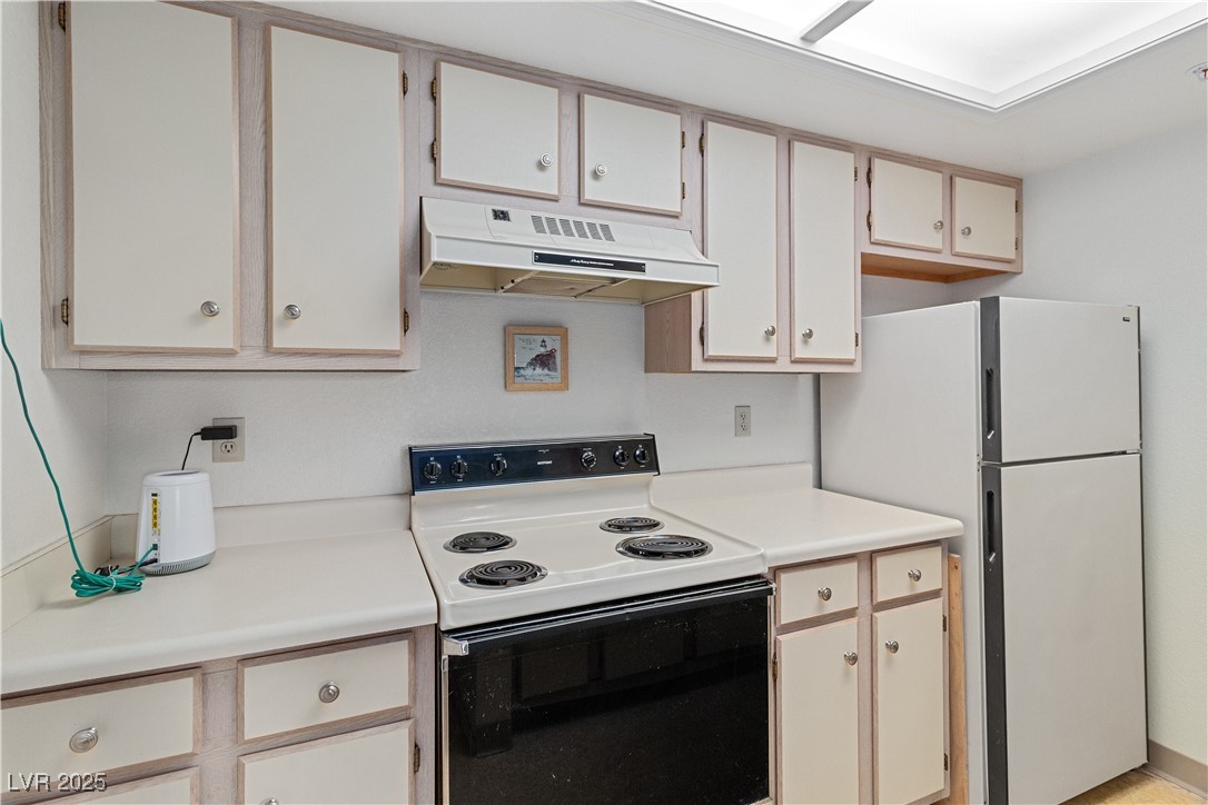 3550 Bay Sands Drive, Unit 1050 Laughlin, NV 89029 - Photo 10 of 71 Kitchen featuring electric range, light countertops, under cabinet range hood, and freestanding refrigerator