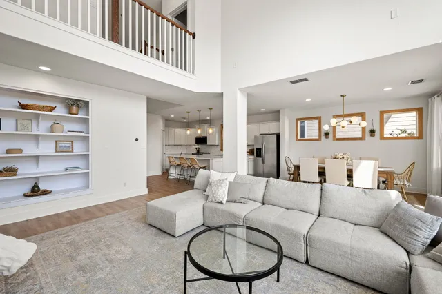 a kitchen with stainless steel appliances kitchen island granite countertop a stove a sink a refrigerator and a dining table with wooden floor