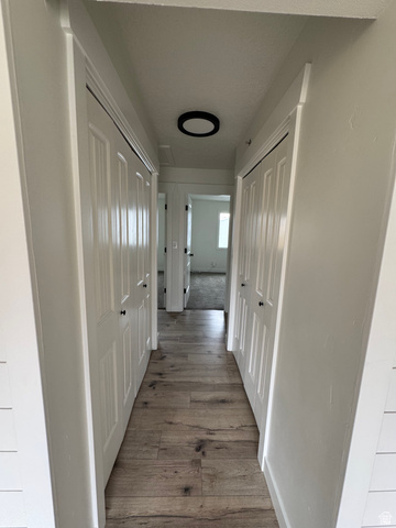 608 South 500 West, Unit 3 Provo, UT 84601 - Photo 20 of 35 Hallway featuring wood-finish flooring, white paneled doors with black hardware, and a modern flush-mount ceiling light fixture