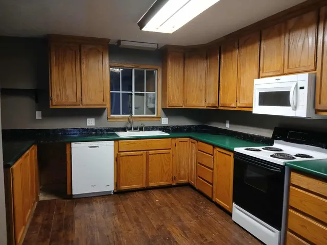 a kitchen with granite countertop wooden cabinets stainless steel appliances and a sink