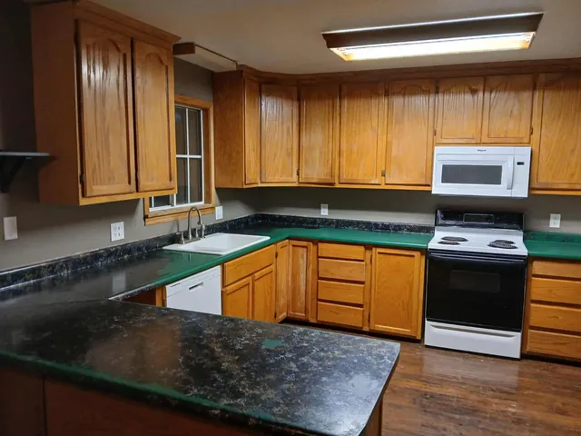 a kitchen with stainless steel appliances granite countertop wooden cabinets a stove top oven a sink and dishwasher