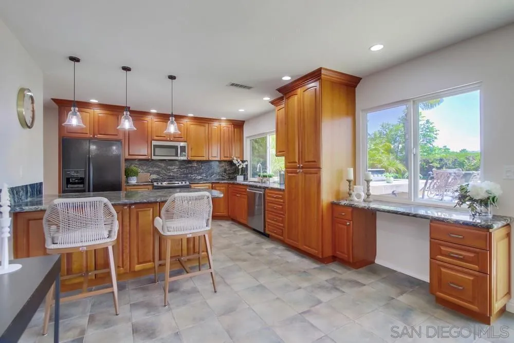 14747 Dash Way Poway, CA 92064 - Photo 15 of 65 a kitchen with granite countertop a table chairs microwave and cabinets