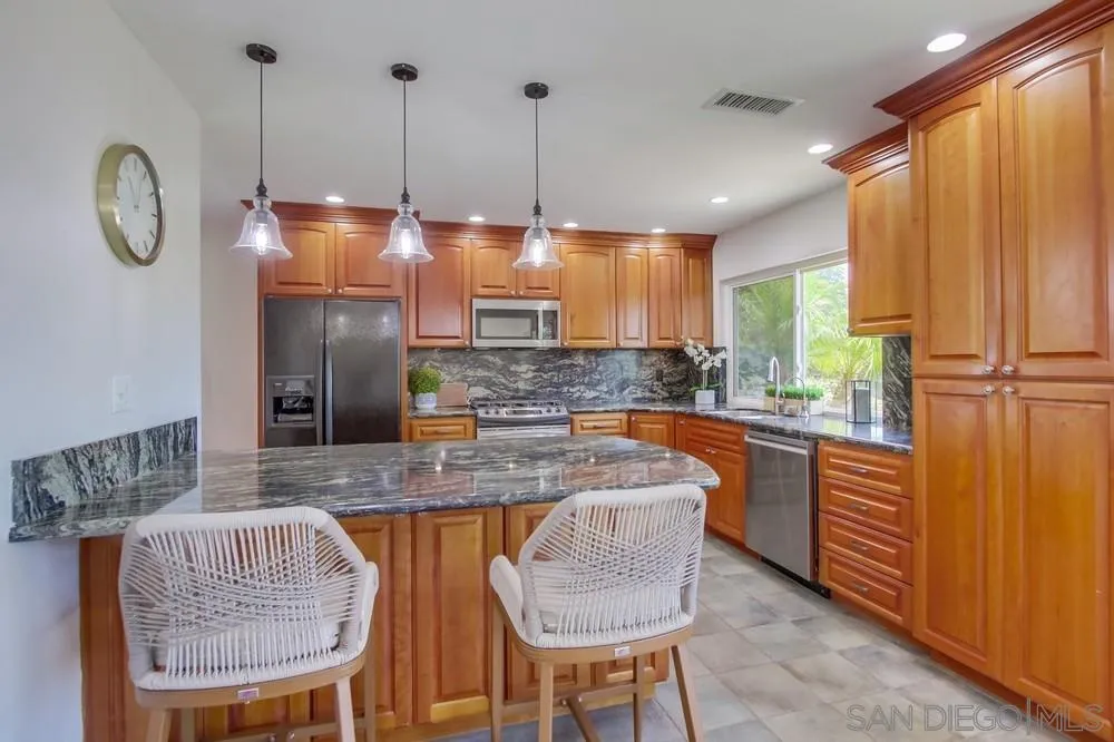 14747 Dash Way Poway, CA 92064 - Photo 46 of 65 a kitchen with stainless steel appliances granite countertop a table chairs and a refrigerator