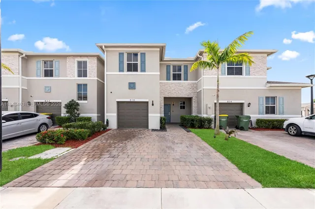 a view of a white house with a yard and table and chairs under an umbrella