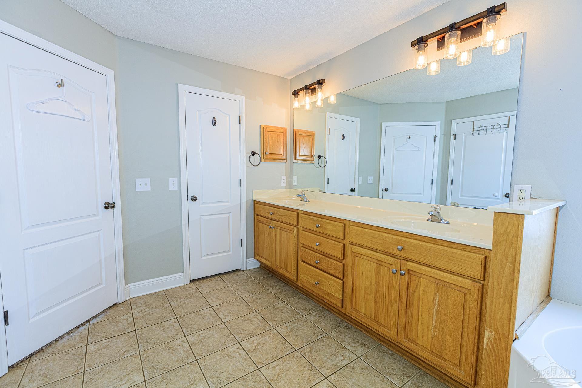 2863 Wallace Lake Road Pace, FL 32571 - Photo 16 of 44 a spacious bathroom with a double vanity sink a mirror and a shower