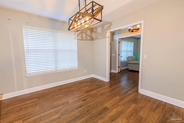 an empty room with wooden floor & windows
