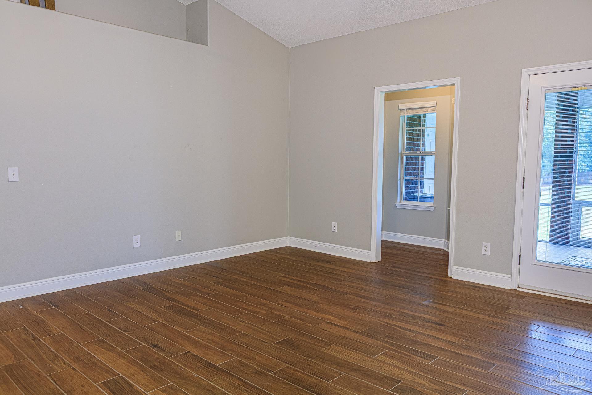 2863 Wallace Lake Road Pace, FL 32571 - Photo 8 of 44 a view of an empty room with wooden floor and a window