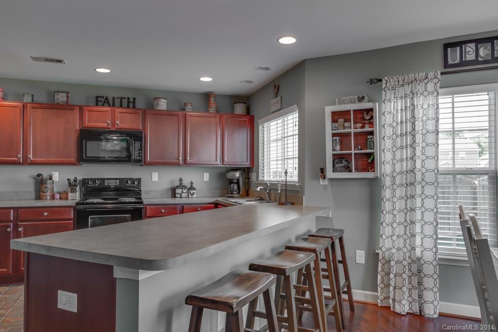4411 Kiddle Lane Monroe, NC 28110 - Photo 9 of 24 a kitchen with stainless steel appliances granite countertop a stove a refrigerator a sink a dining table and chairs with wooden floor